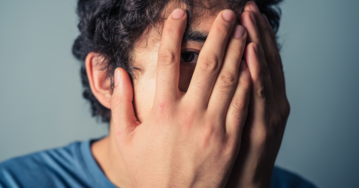 Man peering through fingers. Image © LoloStock / Adobe Stock